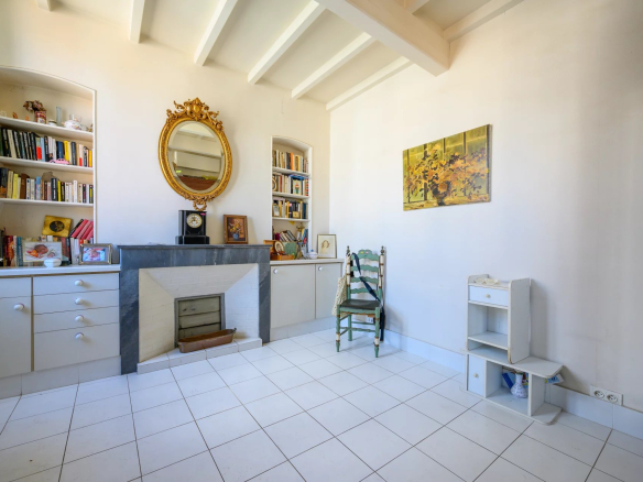 Interior of a 3-room apartment in Cannes with fireplace and shelves, light walls and white tiles.