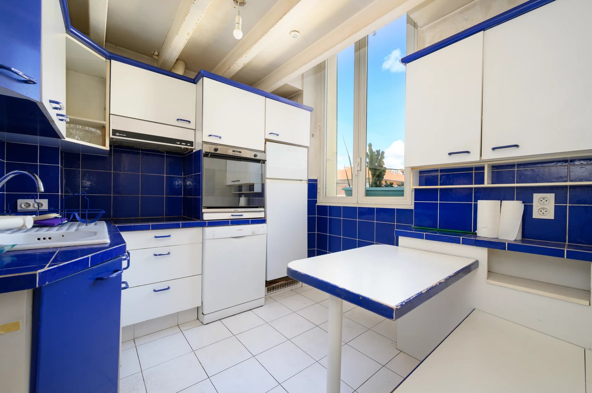 Kitchen of an apartment in Cannes Kitchen of a 3-room apartment in Cannes with blue and white tiles, bright windows.