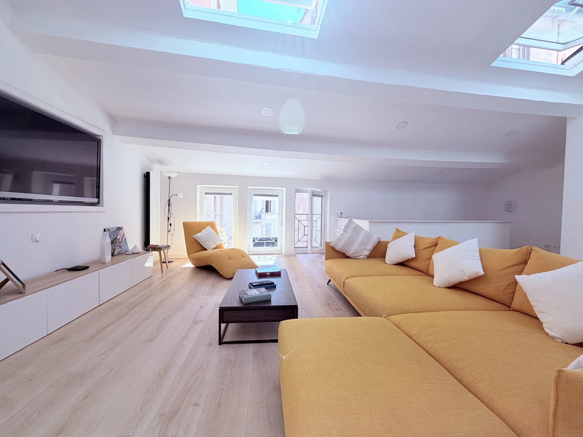 Loft under the eaves in Cannes Interior of a bright loft with a large yellow sofa, television and skylights.