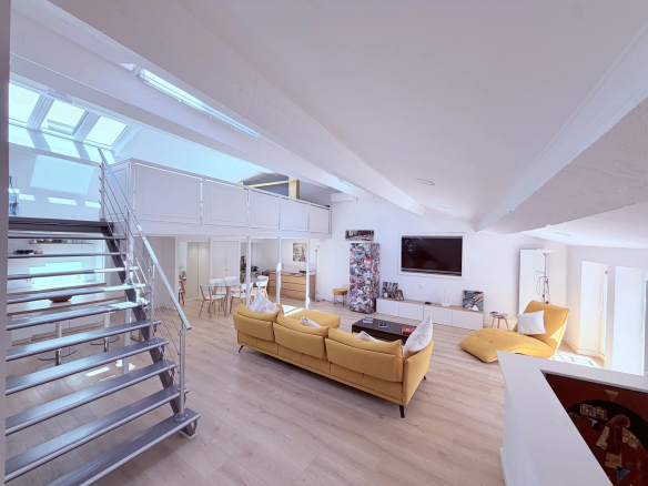 Interior of a bright loft with a modern living room, skylights and a metal staircase in Cannes.