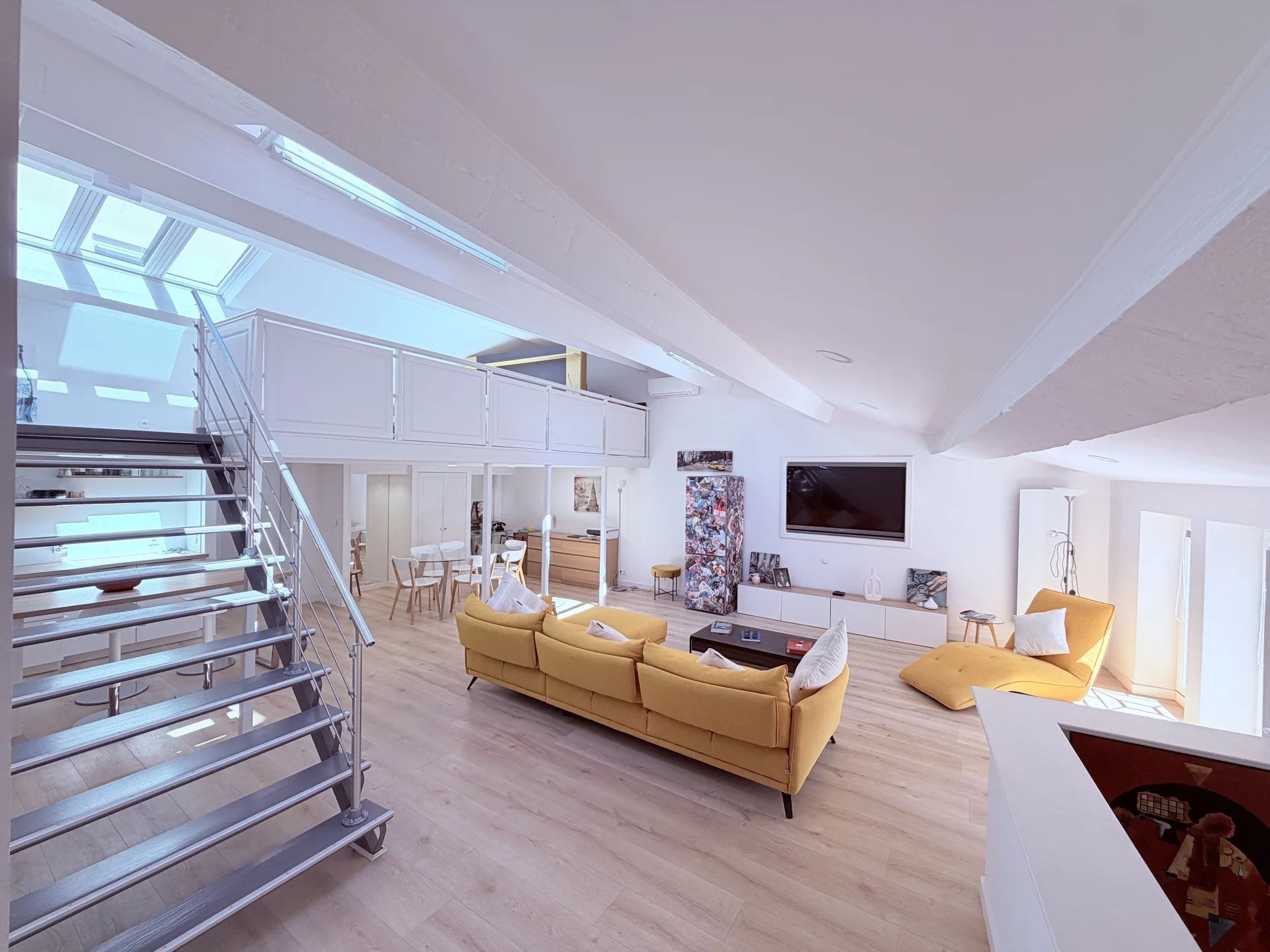 Loft under the eaves in Cannes Interior of a bright loft with a modern living room, skylights and a metal staircase in Cannes.