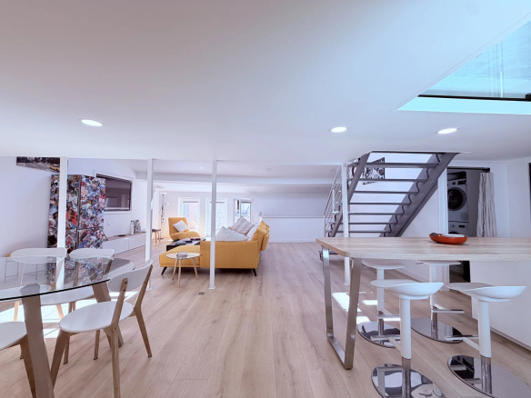 Interior of a modern loft with living room, kitchen and staircase, located under the rooftops in Cannes.