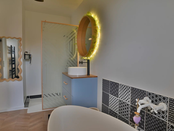 Modern bathroom with bathtub and illuminated mirror in a recently built villa.