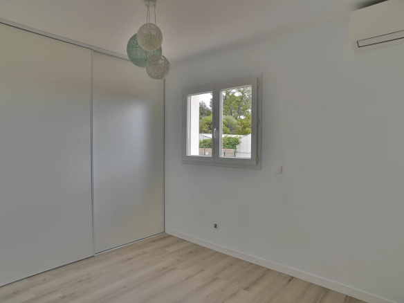 Bedroom in a contemporary villa in Villeneuve-Loubet, with window and parquet flooring.