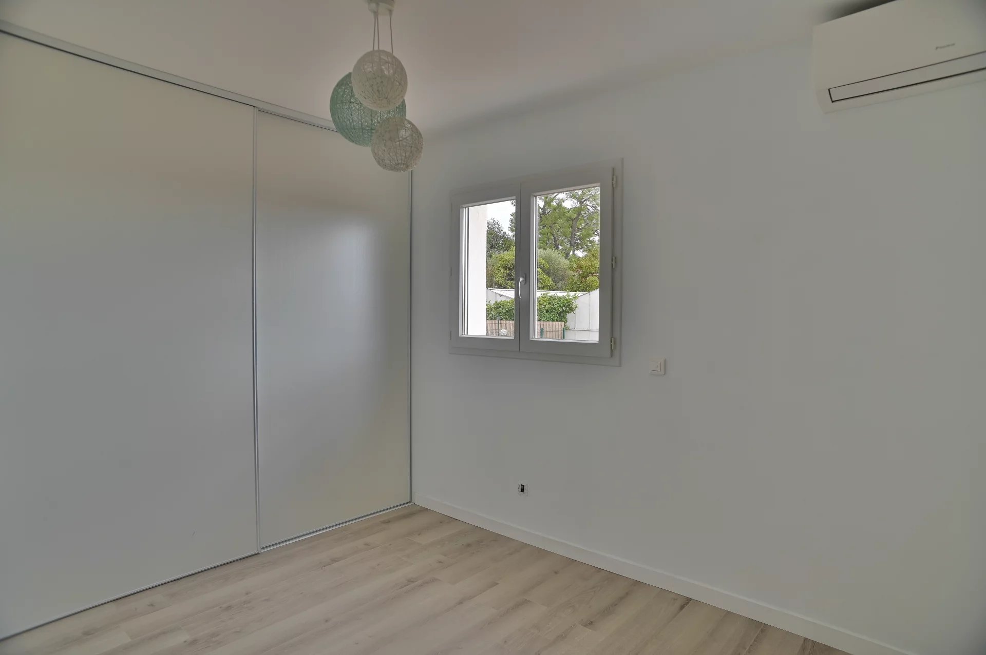 Contemporary villa bedroom Bedroom in a contemporary villa in Villeneuve-Loubet, with window and parquet flooring.