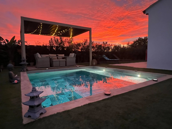 Private swimming pool of a contemporary villa with a colorful sunset sky.