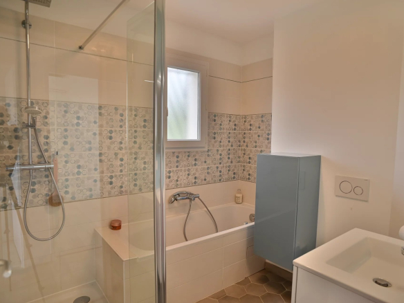 Modern bathroom with shower and bathtub, tiled and decorative tiled flooring.