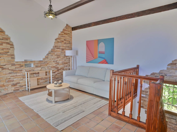 Intérieur d'une villa à Èze avec un salon lumineux, un canapé et des murs en pierre.