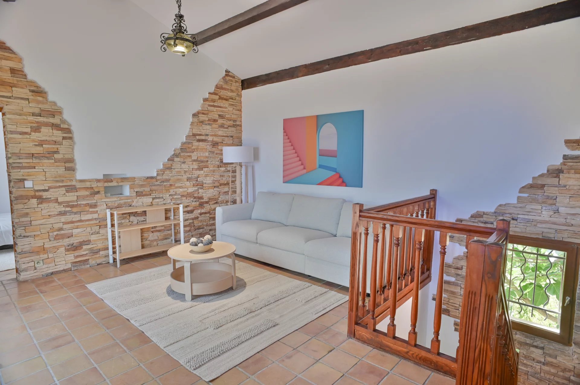 Intérieur d'une villa à Èze avec un salon lumineux, un canapé et des murs en pierre.