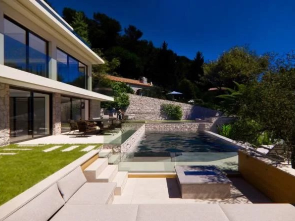 Villa moderne avec piscine et vue mer à Èze, entourée de verdure.