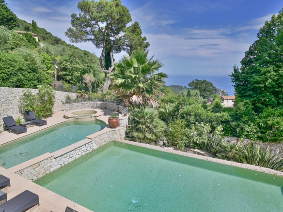 Vue de la piscine et du jardin d'une villa à Èze avec vue sur la mer.