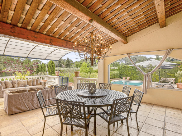 Terrasse couverte avec table et chaises, piscine visible à l'extérieur, propriété en Provence.
