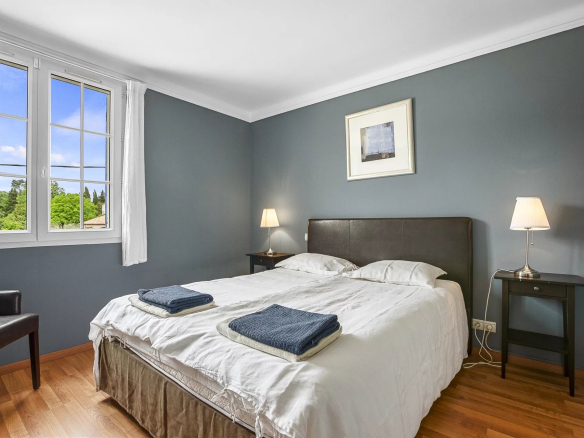 Chambre d'une propriété avec lit double et fenêtres donnant sur un jardin.