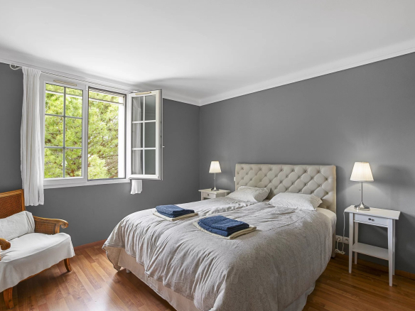 Chambre d'une propriété avec lit double, fenêtres ouvertes et décoration moderne.