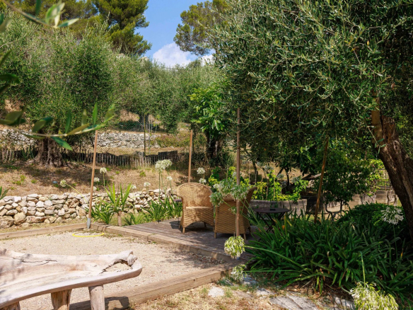 Jardin paysager d'une bastide rénovée à Mougins avec des chaises en osier et des plantes.