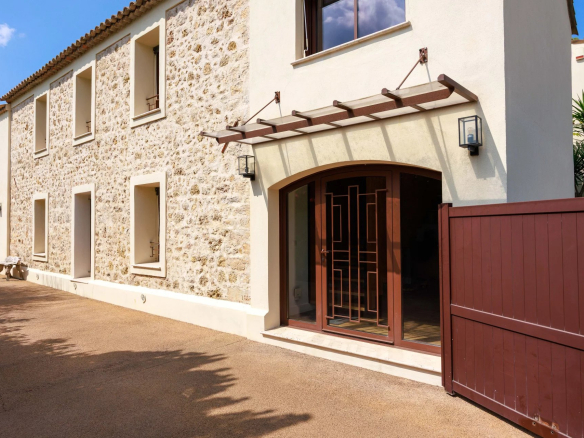 Entrée d'une bastide rénovée de 1887 à Mougins, avec façade en pierre et portail en bois.