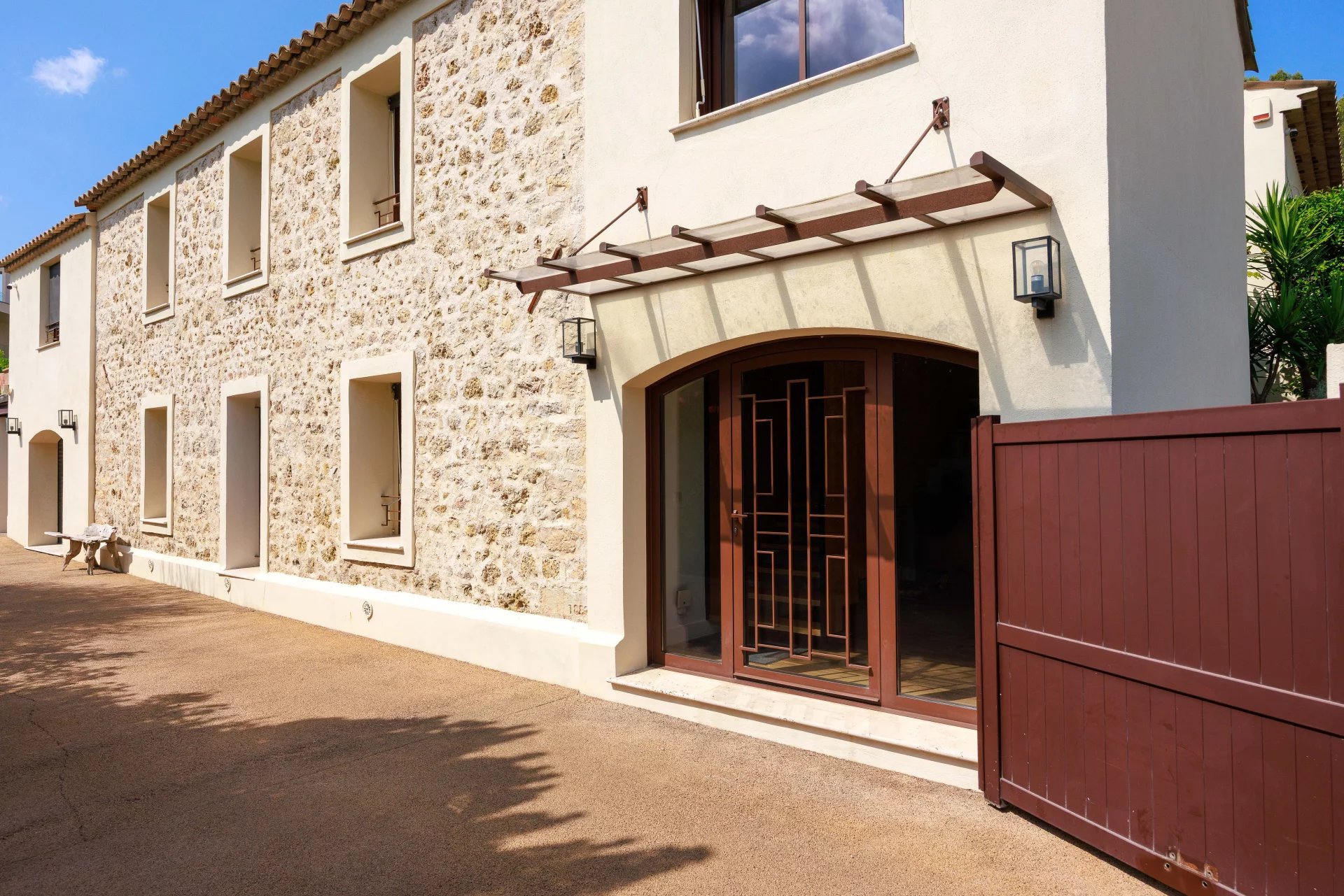 Bastide rénovée à Mougins Entrée d'une bastide rénovée de 1887 à Mougins, avec façade en pierre et portail en bois.