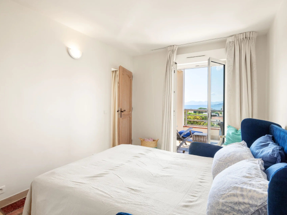 Chambre d'un appartement à Antibes avec vue sur la mer et accès à un balcon.