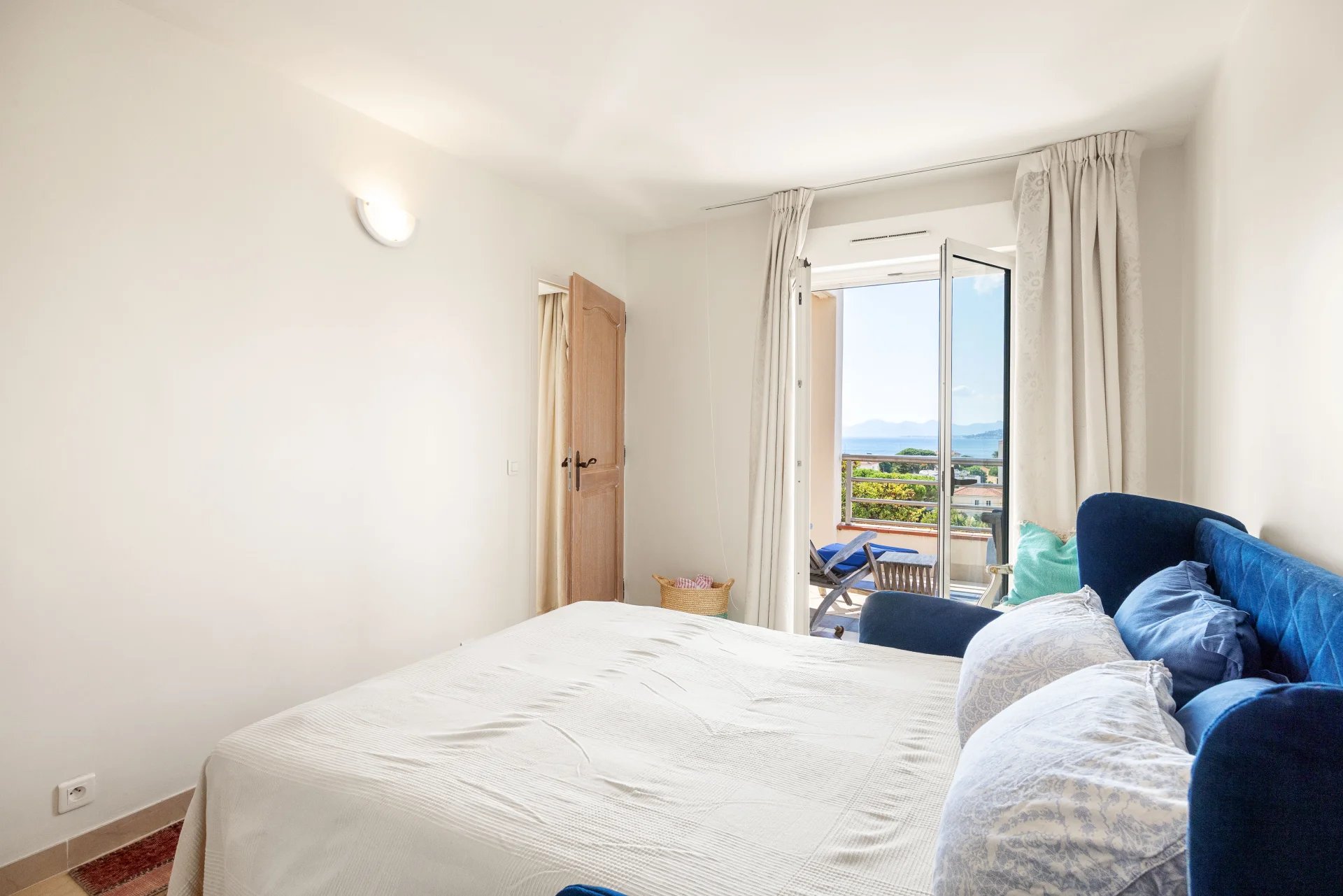 Chambre d'un appartement à Antibes avec vue sur la mer et accès à un balcon.