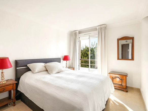 Chambre d'un appartement avec lit double, lampes de chevet et balcon à Antibes.
