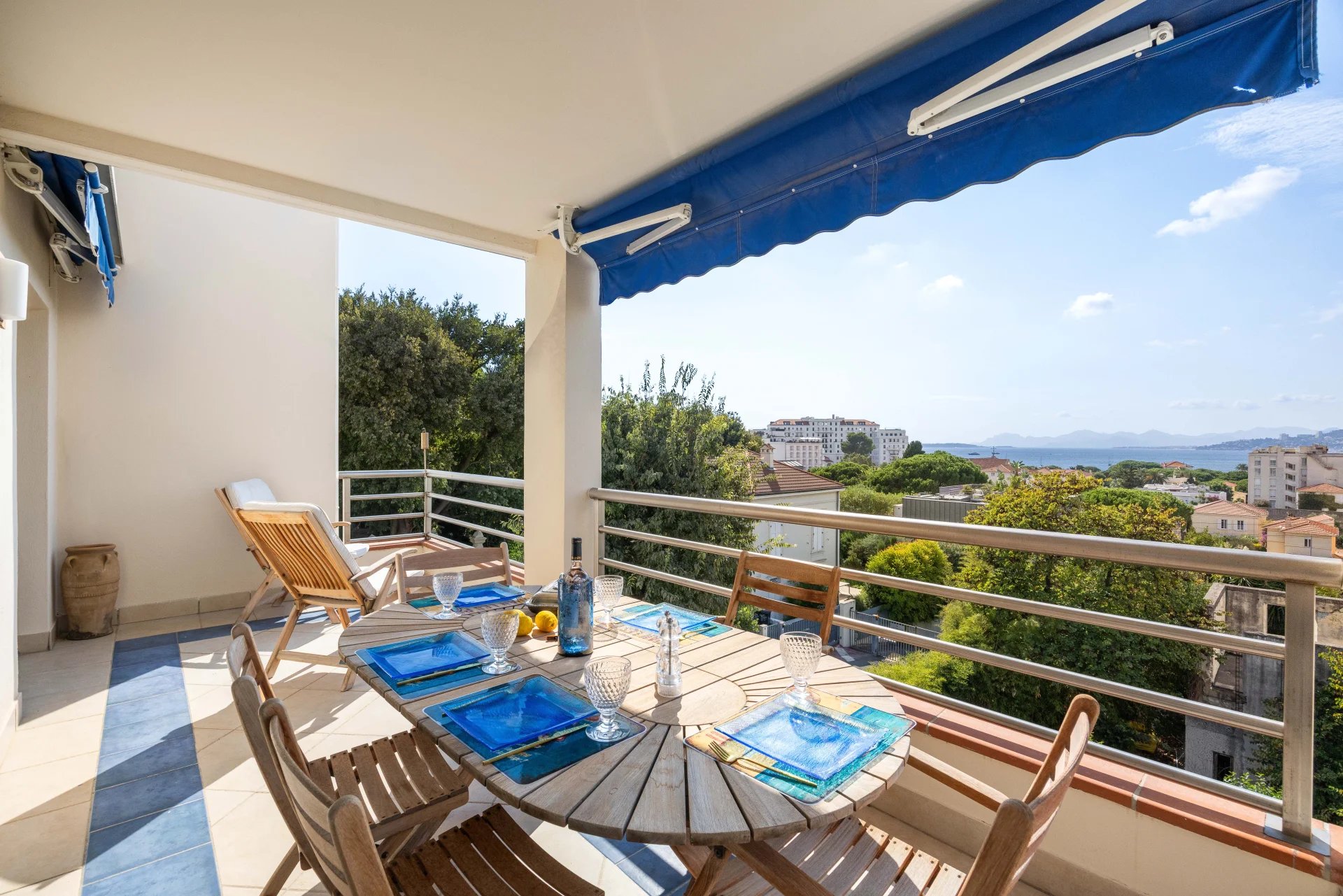 Terrasse d'un appartement avec vue panoramique sur la mer, mobilier de jardin et table dressée.