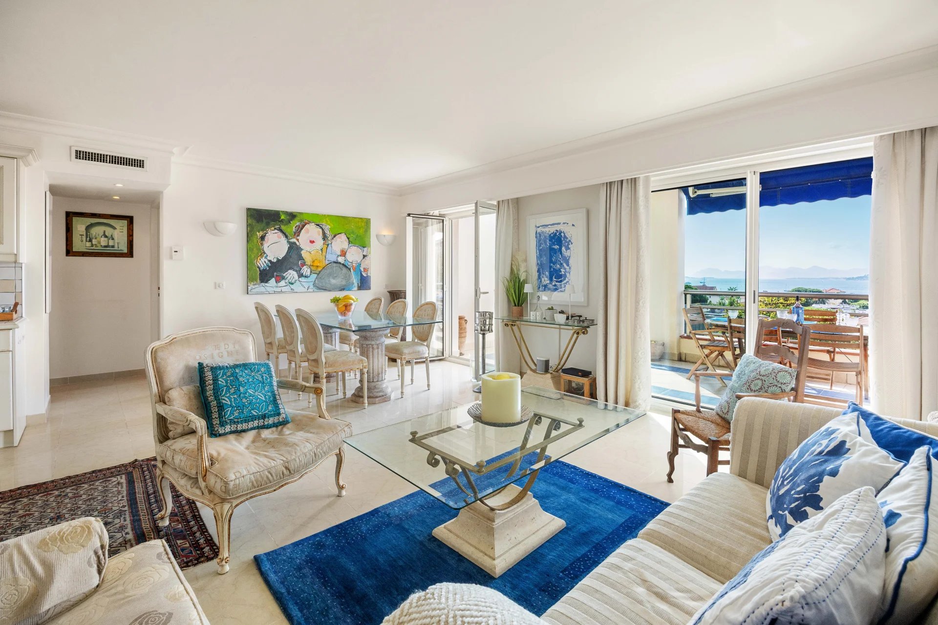 Intérieur d'un appartement lumineux avec salon, salle à manger et vue sur la mer à Antibes.