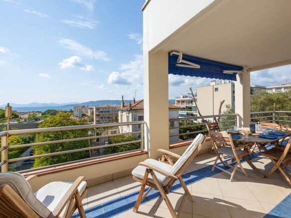 Terrasse d'un appartement avec vue panoramique sur la mer à Antibes, mobilier de jardin présent.