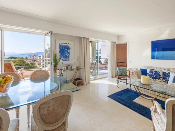 Intérieur d'un appartement lumineux avec salon et salle à manger, vue sur la mer depuis la terrasse.