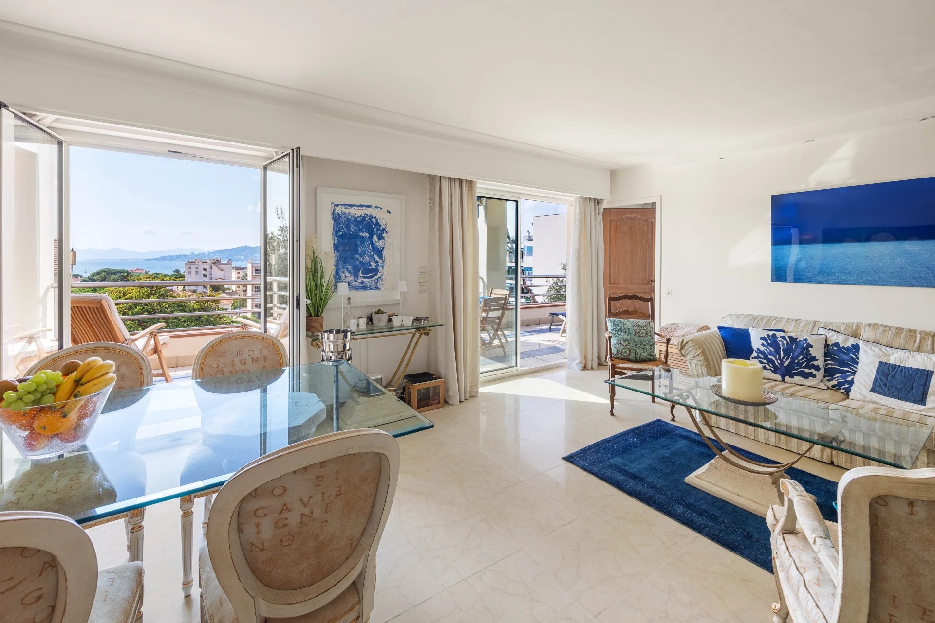 Intérieur d'un appartement lumineux avec salon et salle à manger, vue sur la mer depuis la terrasse.