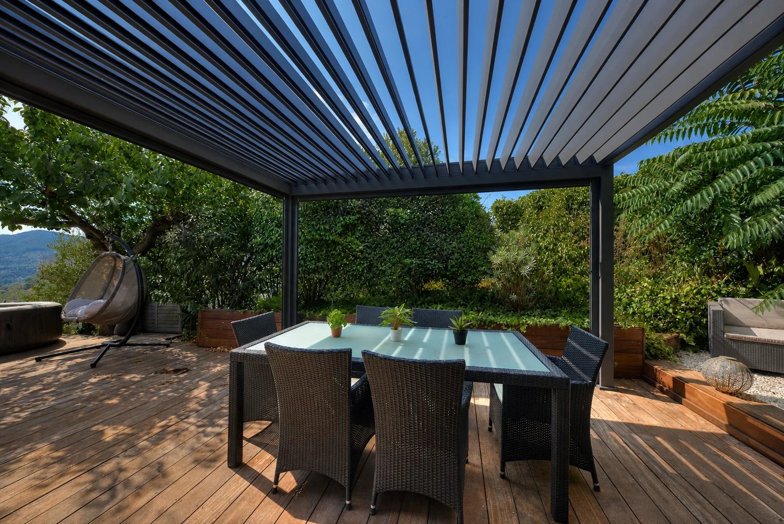 Wooden terrace with garden furniture and pergola, overlooking the surrounding nature.