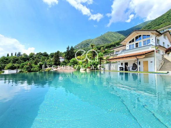 Luxurious villa by an expansive infinity pool with a white two-story house, terracotta roof, and lush green hills in the background.