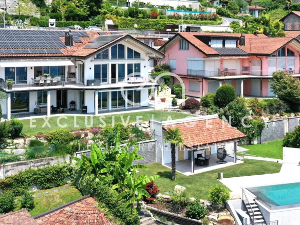 Luxurious hillside villas with red-tiled roofs, glass terraces, and a rectangular pool in the foreground, surrounded by lush greenery.