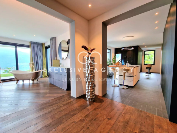 Luxurious open-concept living space with bathtub by floor-to-ceiling windows and an island kitchen.