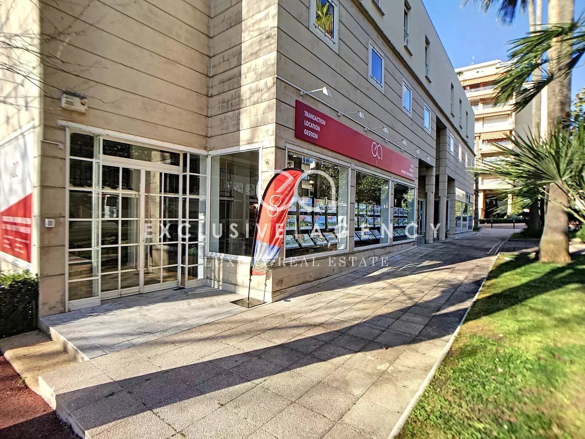 Facade of a modern building with shop windows and an outdoor space in Cannes.