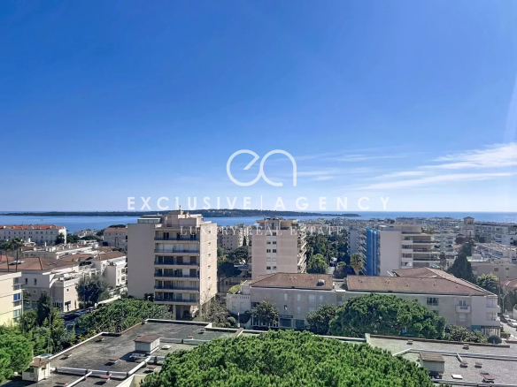 Panoramic view of Cannes from a top floor, with buildings and the sea in the distance.