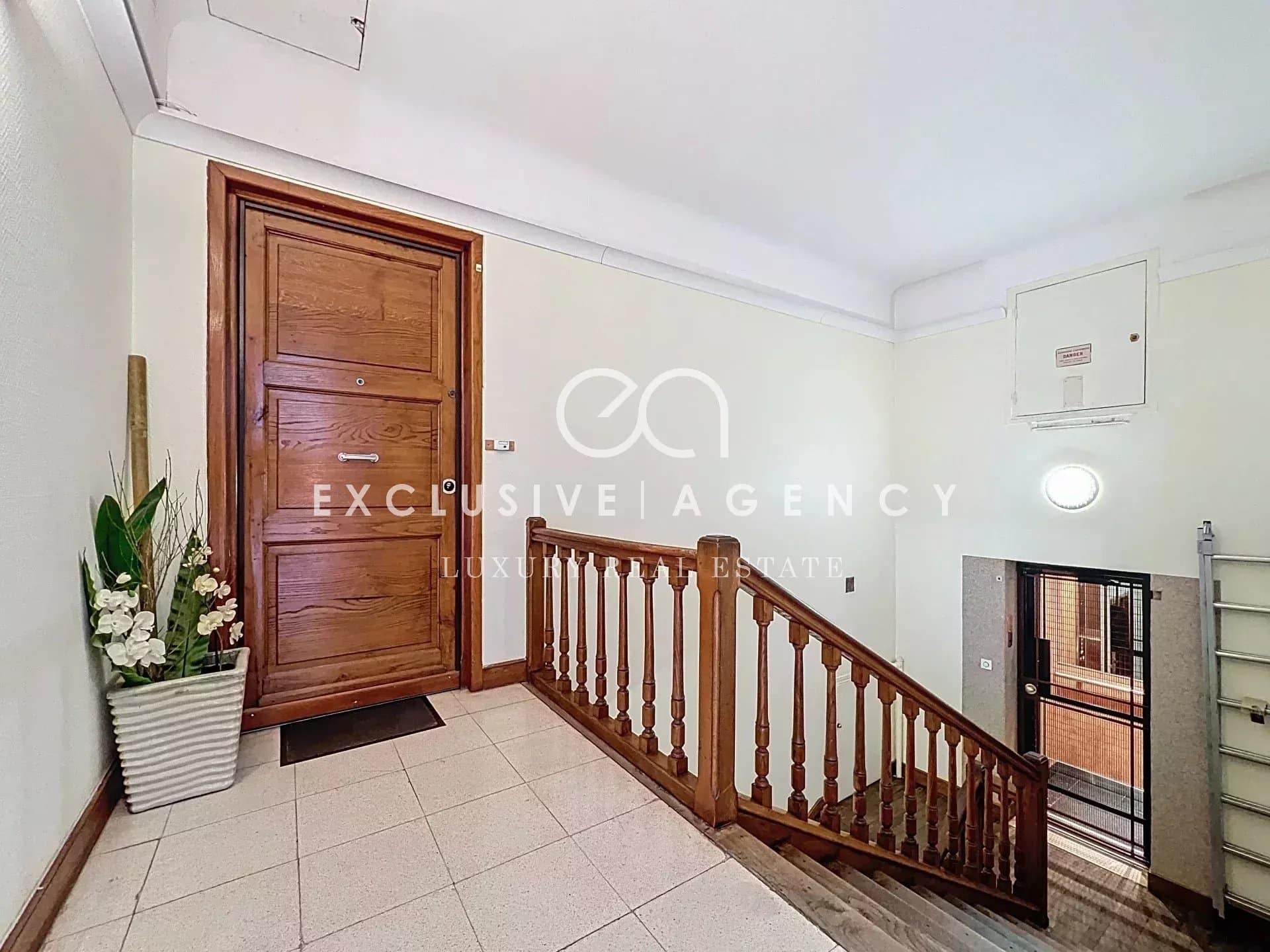 Entrance to a bourgeois building in Cannes with wooden staircase and wooden front door.
