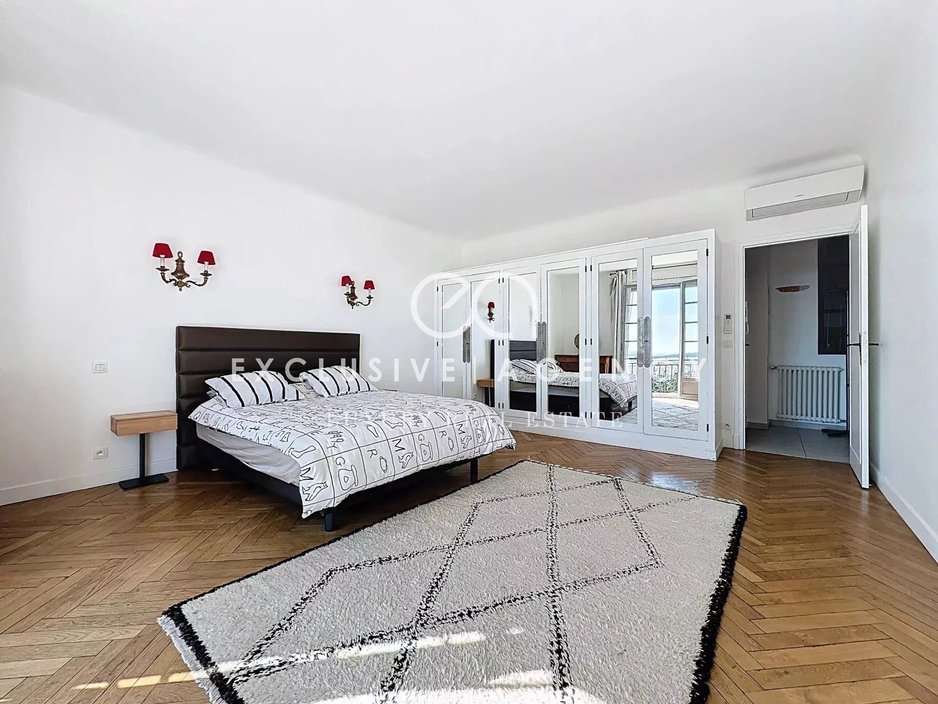 Spacious room with bed and mirror in an apartment in Cannes.