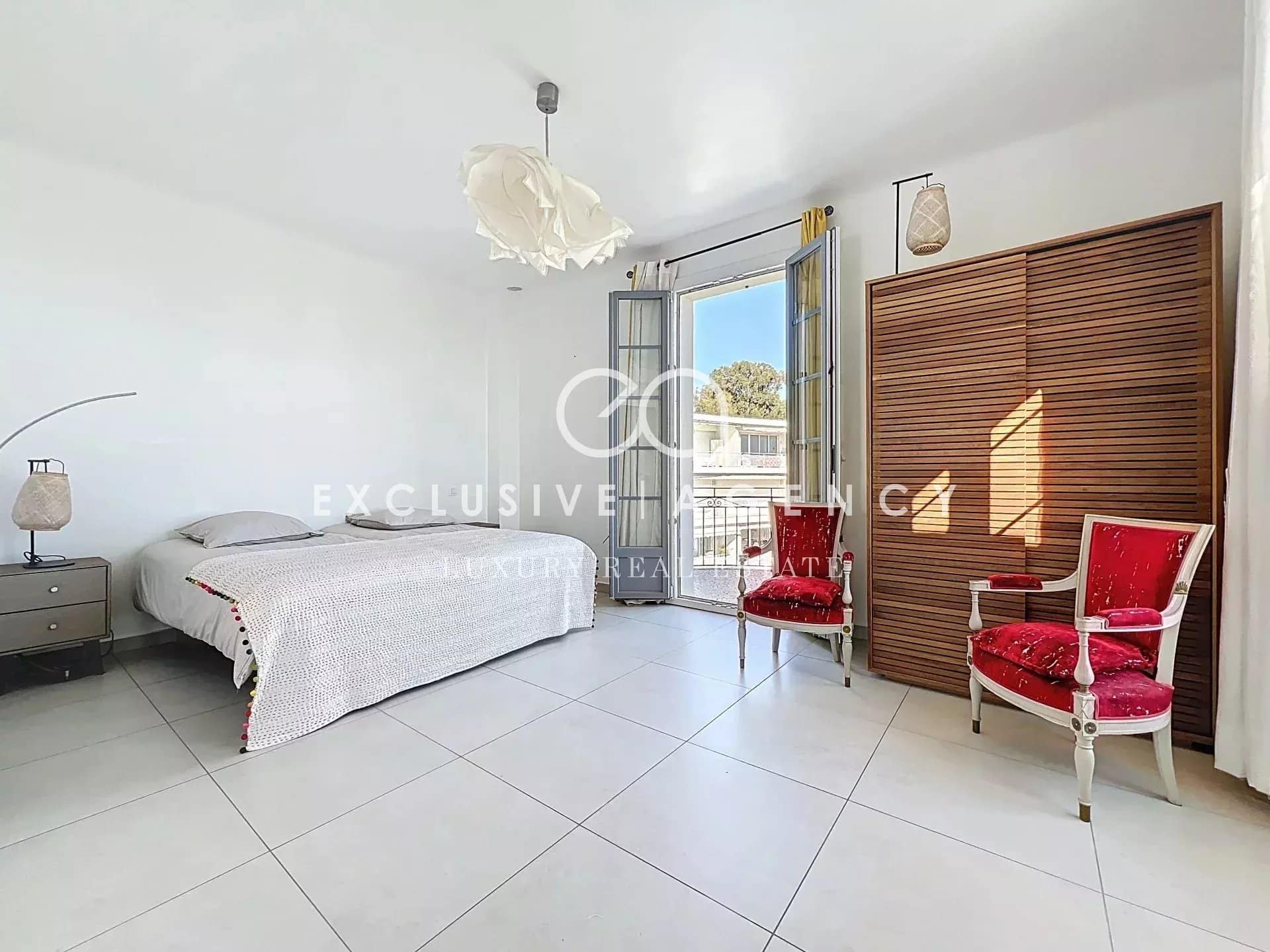 Bright bedroom in a Cannes apartment with balcony and elegant furniture.