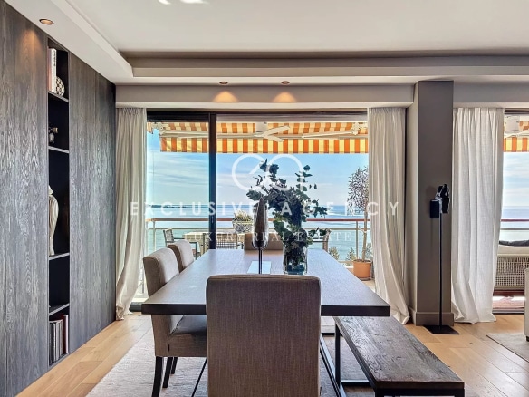 Interior of a modern apartment with sea view, dining table and bay windows.