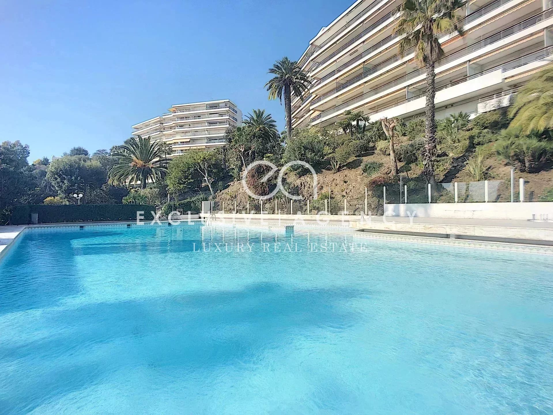 Swimming pool of a luxury residence in Cannes Eden with sea view and palm trees.