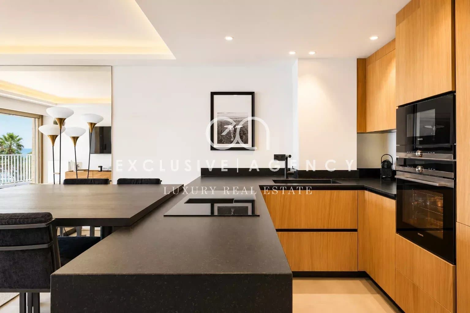 Cuisine rénovée d’un appartement à Cannes Cuisine moderne avec plan de travail en noir et meubles en bois dans un appartement à Cannes.