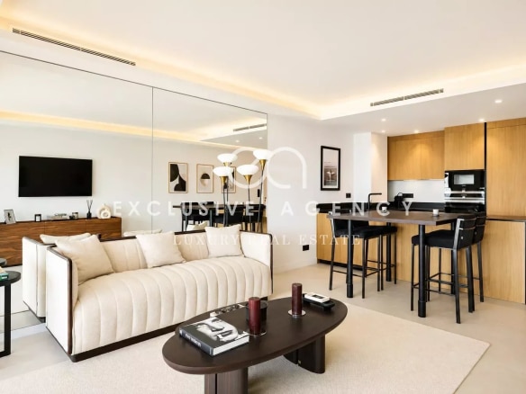 Intérieur d'un appartement moderne avec salon et cuisine ouverte, vue sur la mer.
