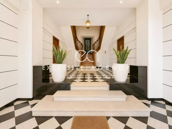 Entrée d'une maison bourgeoise à Cannes avec un sol en damier et des plantes décoratives.