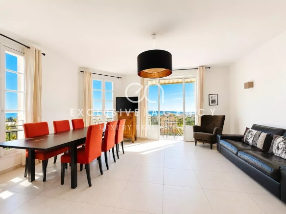 Salon lumineux d'un appartement à Cannes avec vue mer, table à manger et canapé.