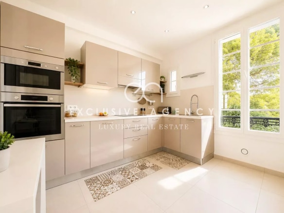 Cuisine moderne dans un appartement à Cannes, avec des meubles clairs et des fenêtres offrant une vue sur l'extérieur.