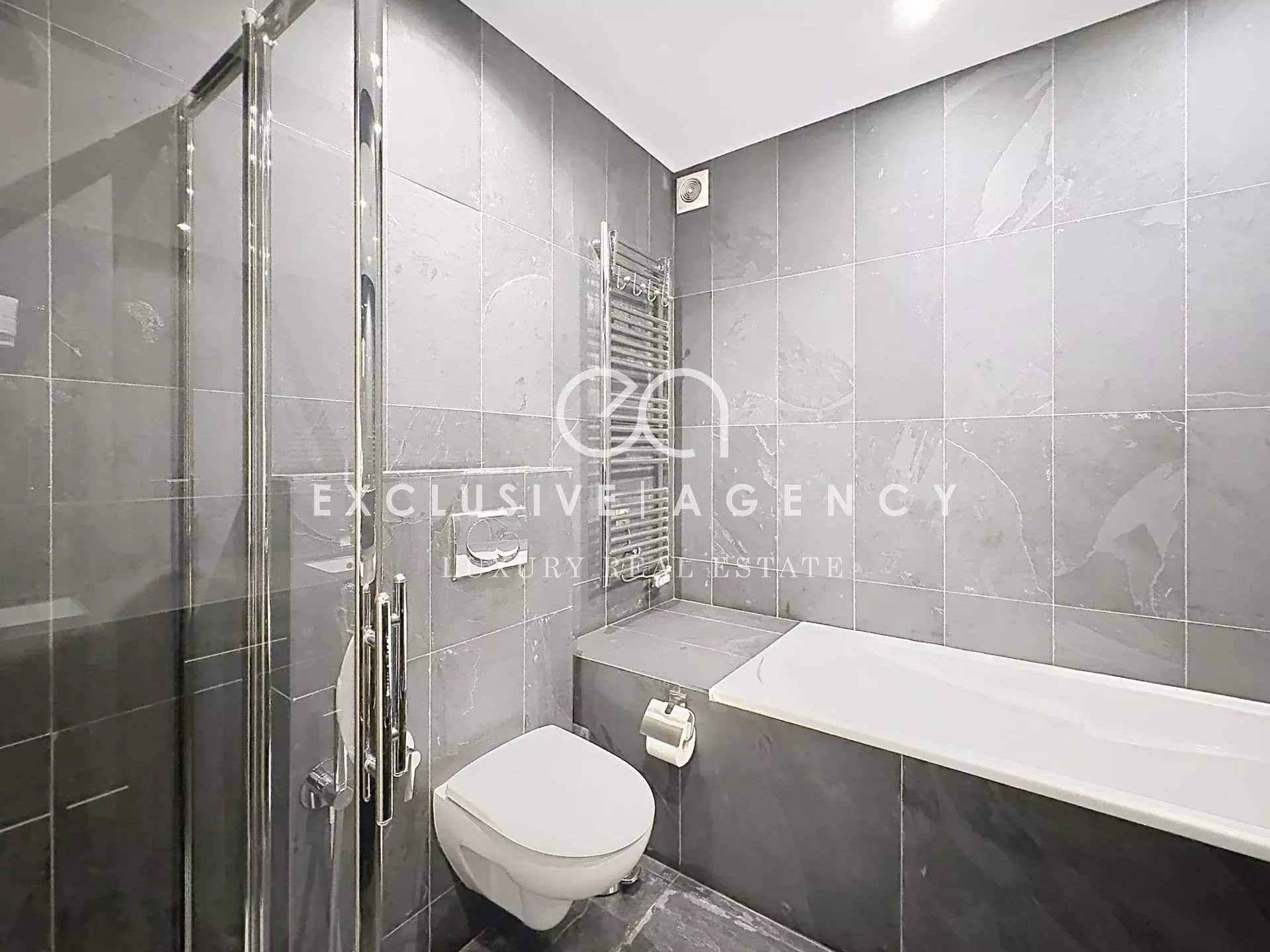 Salle de bain moderne avec douche et baignoire, carrelage gris