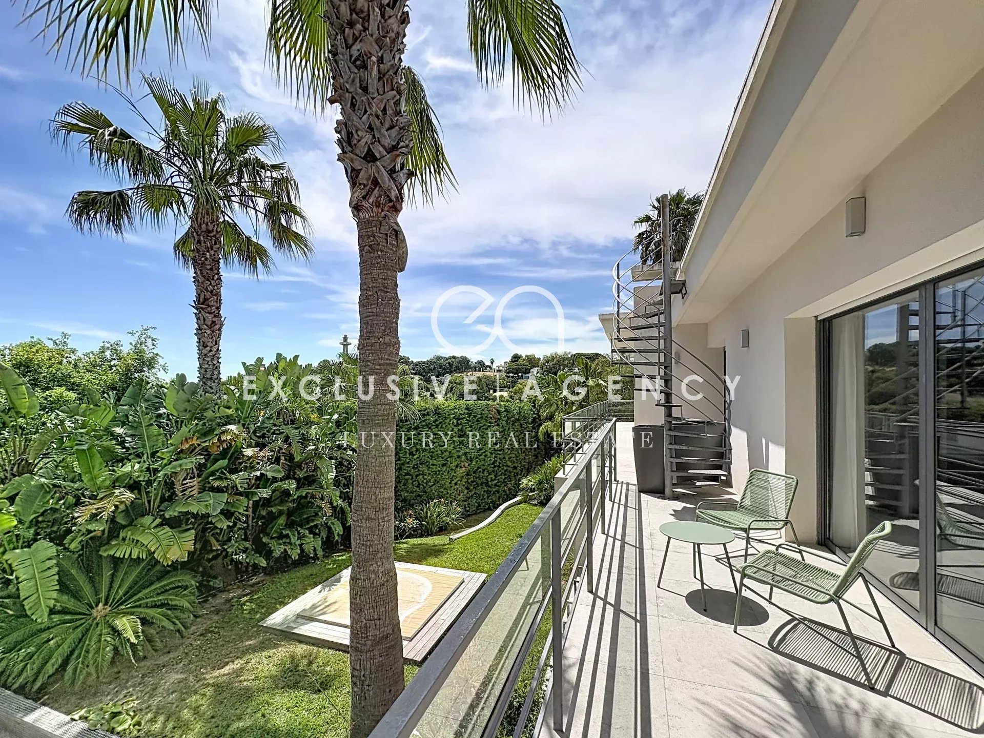 Terrasse d'une villa californienne à Cannes avec vue sur la verdure et palmier.