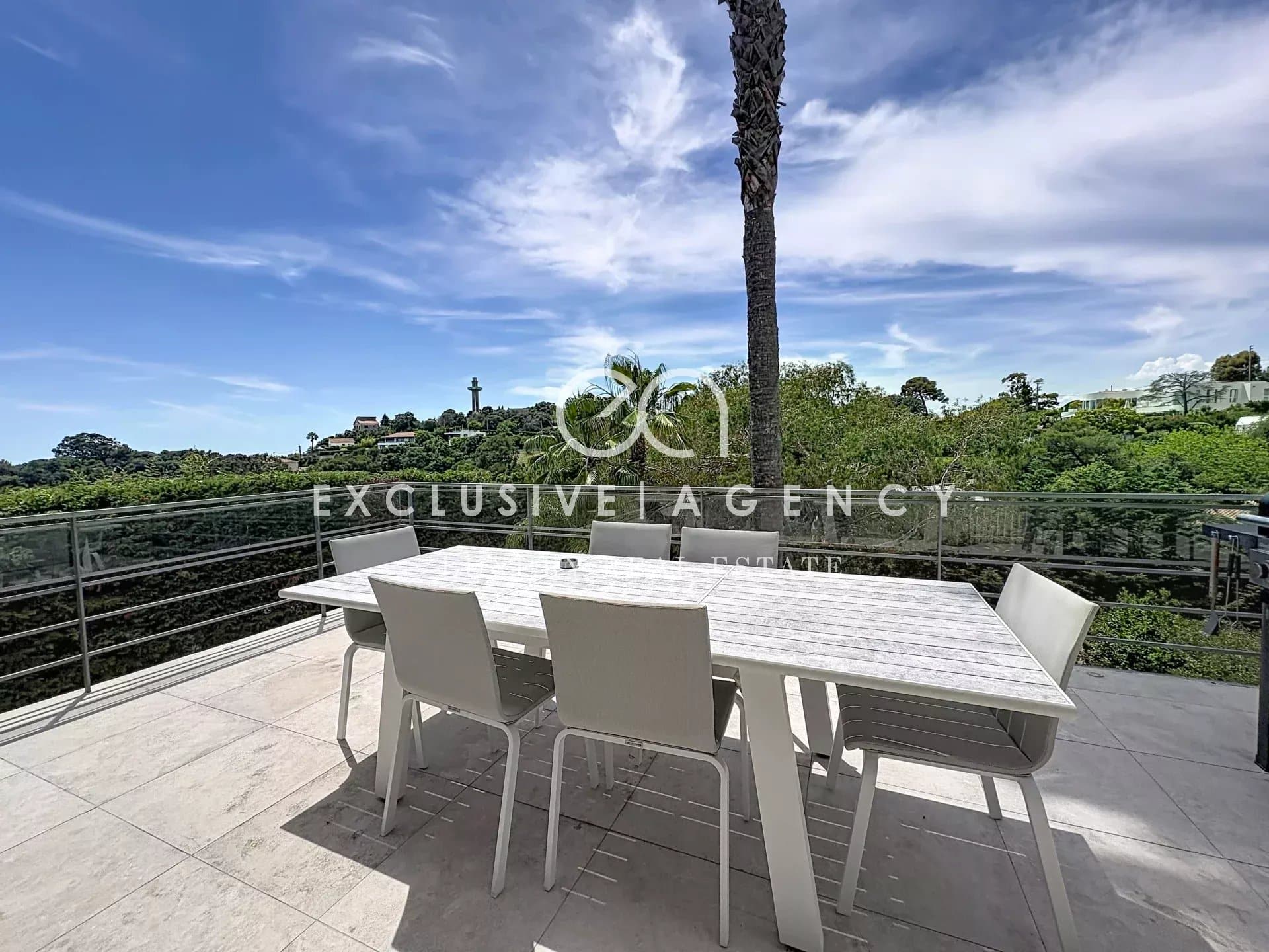 Terrasse d'une villa californienne à Cannes avec mobilier de jardin et vue sur la verdure.