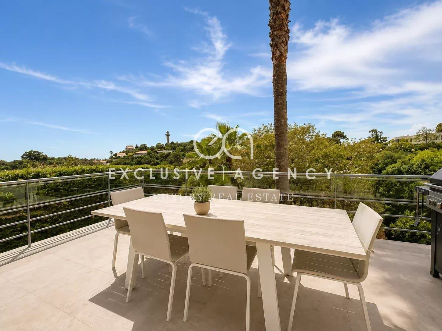 Terrasse d'une villa californienne à Cannes avec table et chaises, vue sur la nature.