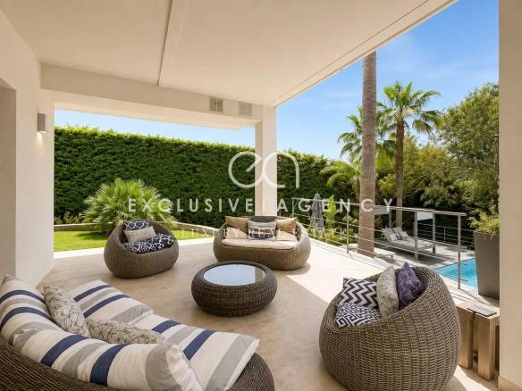 Terrasse d'une villa californienne avec mobilier en rotin et piscine en arrière-plan.